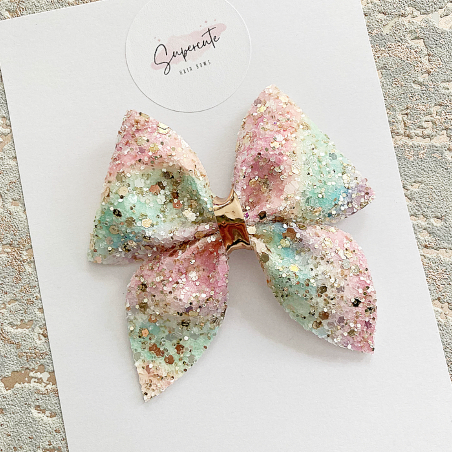 A beautiful ombré rainbow glitter hair bow with gold sparkles in a sailor style