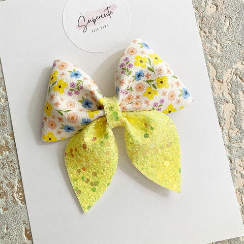 a floral and lemon hair bow made from glitter fabric in a sailor bow shape