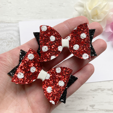 a pair of red and white polka dot glitter pig tail bows around 2.5" wide with black glitter tails 