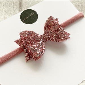 dusky pink glitter bow on a soft stretchy baby headband 